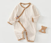Striped baby romper with brown accents and a matching toy on a white background