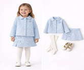 Child wearing a light blue outfit with matching jacket and skirt, standing next to the outfit pieces on a white background.
